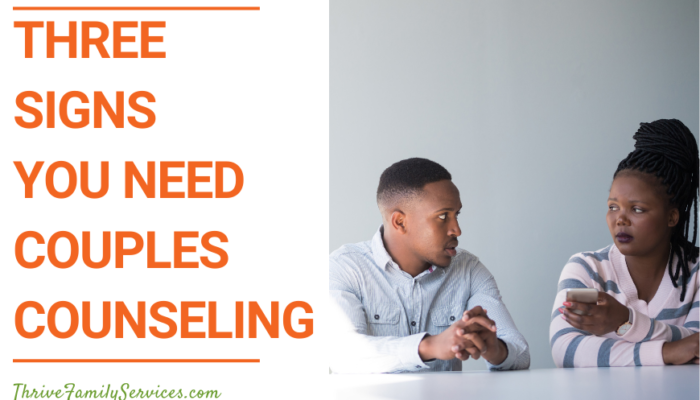 orange text that reads "3 Signs You Need Couples Counseling" next to a photo of a man and a woman of color seated at a white counter. she has her arms crossed and he is holding his hands on the table. They look upset. | Aurora Marriage Counseling