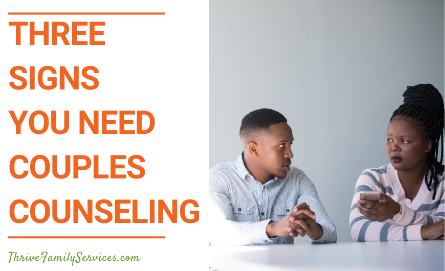 orange text that reads "3 Signs You Need Couples Counseling" next to a photo of a man and a woman of color seated at a white counter. she has her arms crossed and he is holding his hands on the table. They look upset. | Aurora Marriage Counseling