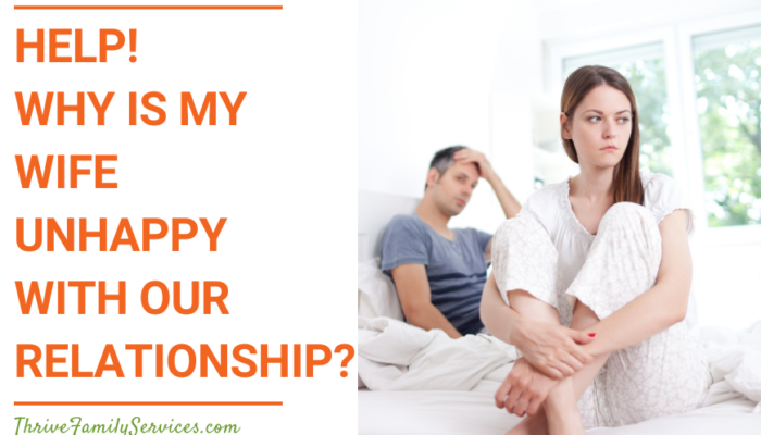 Orange text on a white background that reads "Help! Why Is My Wife Unhappy With Our Relationship?" to the left of a photo of an unhappy looking couple sitting on a bed. | Greenwood Village Marriage Counseling