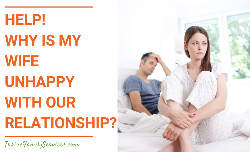 Orange text on a white background that reads "Help! Why Is My Wife Unhappy With Our Relationship?" to the left of a photo of an unhappy looking couple sitting on a bed. | Greenwood Village Marriage Counseling