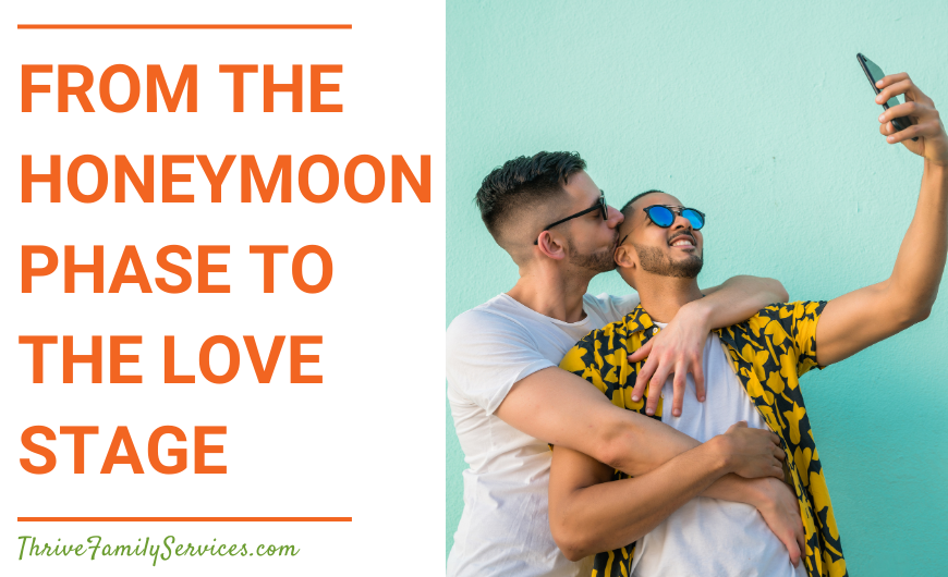 Orange text that reads "From the Honeymoon Phase to the Love Stage" to the left of a photo of two men embracing and posing for a selfie. They are posing in front of an aqua colored wall and smiling with their arms wrapped around each other. | Lone Tree Colorado Marriage Therapy