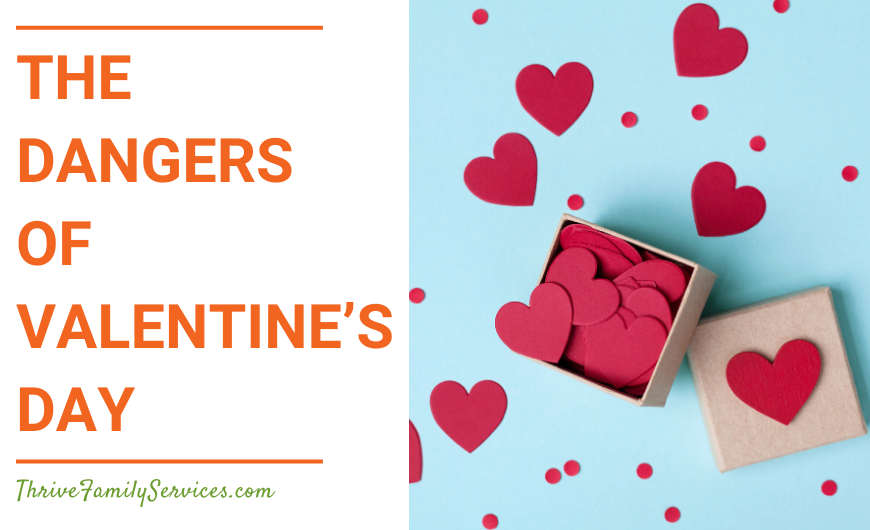 Orange text that reads "The Dangers of Valentine's Day" to the left of a photo of a cardboard box of red paper hearts open on a light blue background. | Denver Colorado Relationship Counselor