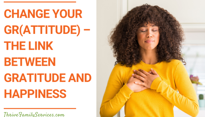 Orange text on a white background that reads "Change your Gr(Attitude) - The Link Between Gratitude and Happiness" to the left of a photo of a Black woman in a yellow long sleeved shirt with her hands over her heart and her eyes closed. | Aurora Colorado Emotionally Focused Therapy