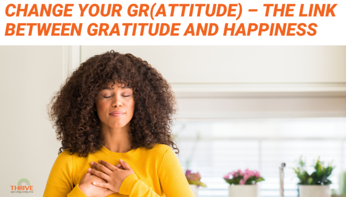 Orange text on a white background that reads "Change your Gr(Attitude) - The Link Between Gratitude and Happiness" above a photo of a Black woman in a yellow long sleeved shirt with her hands over her heart and her eyes closed.