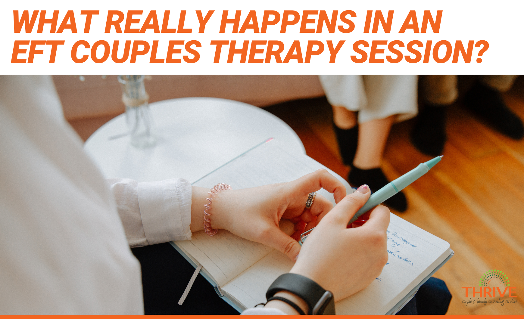 Orange text on a white background that reads "What Really Happens In an EFT Couples Therapy Session?" above a photo of a close up of a therapist's hands writing on a notepad. In the background we can see the legs of a couple seated on a couch.