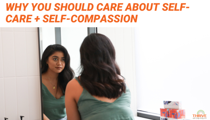 Orange text that reads "Why You Should Care About Self-Care + Self-Compassion" above a photo of a woman with brown skin and hair looking in a mirror.