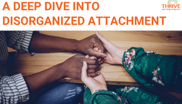 Graphic that reads "A Deep Dive Into Disorganized Attachment" in orange text above a stock photo of a white person and a Black person's hands clasped together on a table. | Couples Counseling Centennial Colorado
